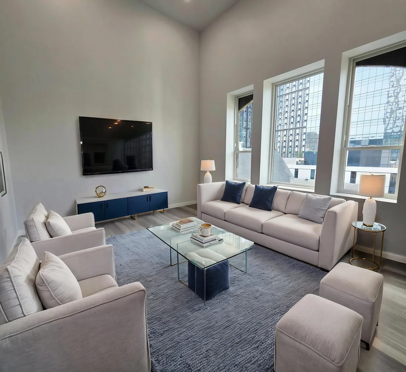 Studio apartment interior with high ceilings, large windows, and a staged living area